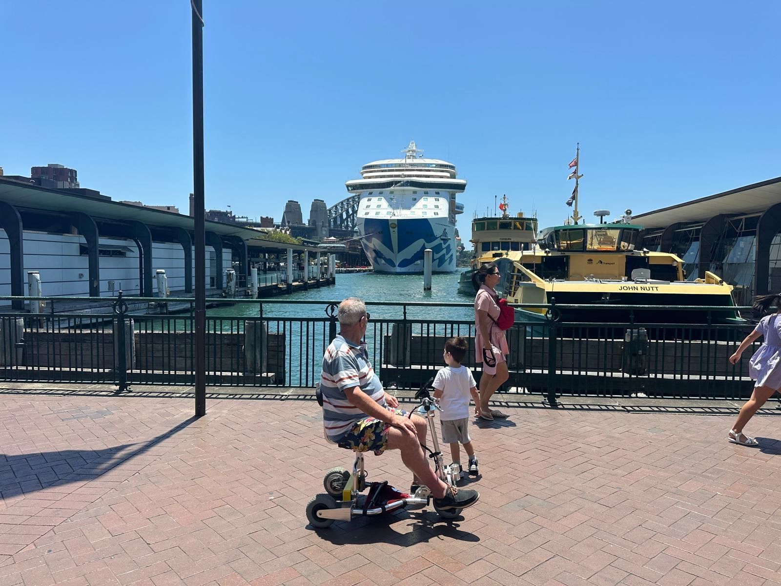 Man sitting on travel scooter looking at cruise ship
