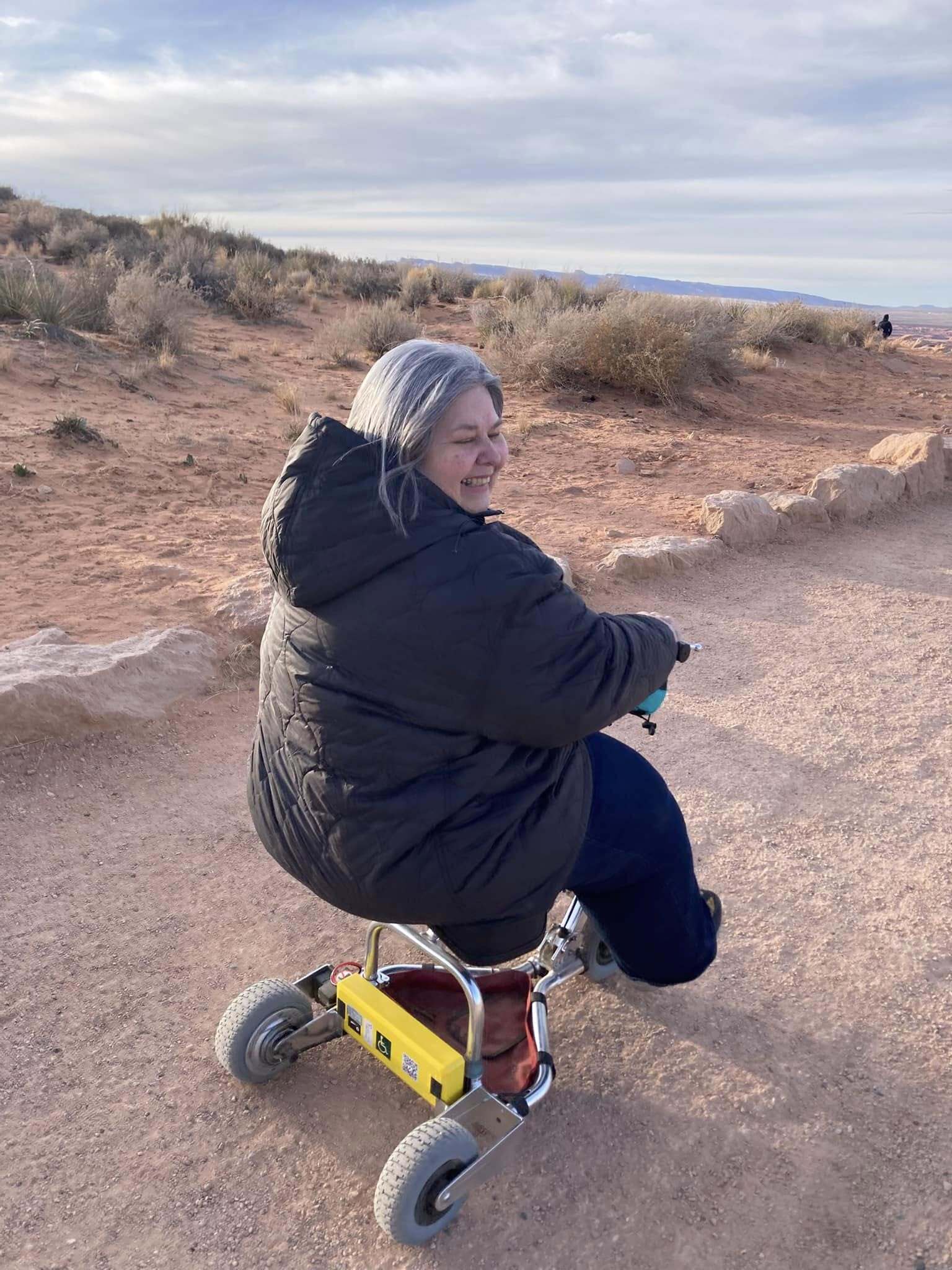 Woman riding travel scooter in the desert.