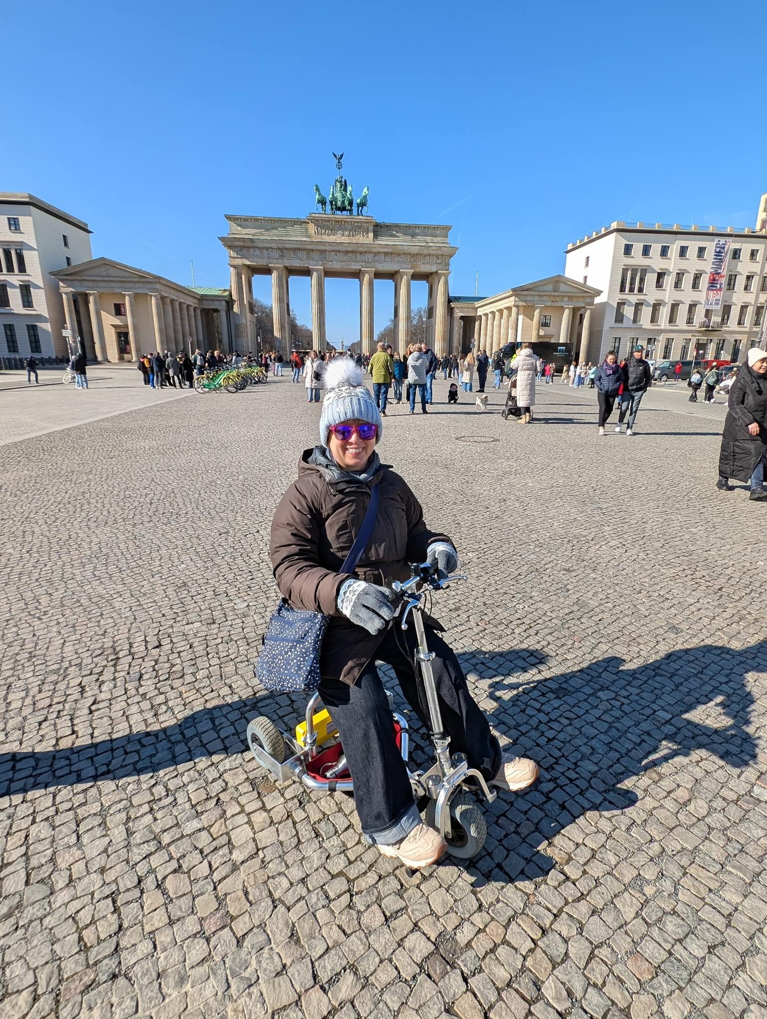 Woman dressed in warm clothing riding travel scooter.