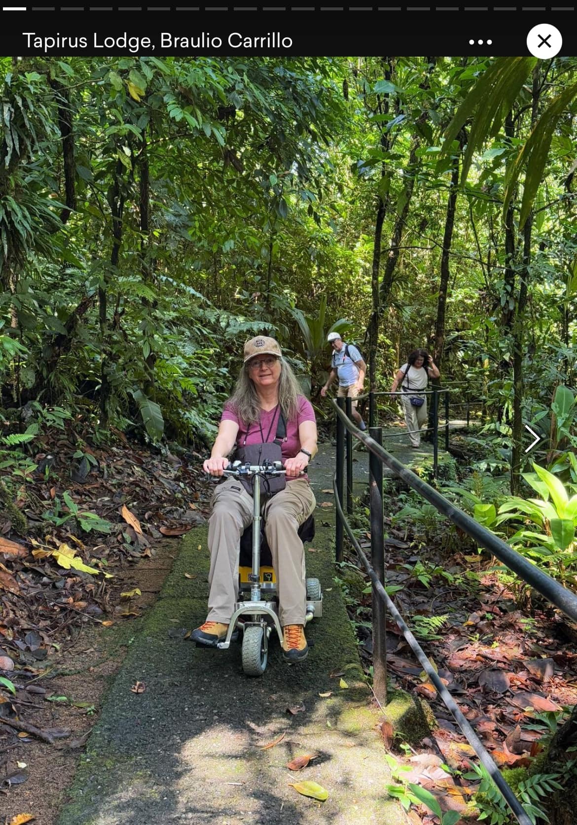 Woman riding travel scooter in wooded area.