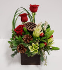 A cheerful holiday centerpiece with red roses, white lilies, pinecones, and other Christmas ornament pieces to brighten your days  A cheerful holiday centerpiece with red roses, white lilies, pinecones, and other Christmas ornament pieces to brighten your days