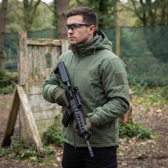 Man wearing Kombat UK Delta - Water Resistant SF Kom-Tex Jacket in Olive Green at woodland airsoft site