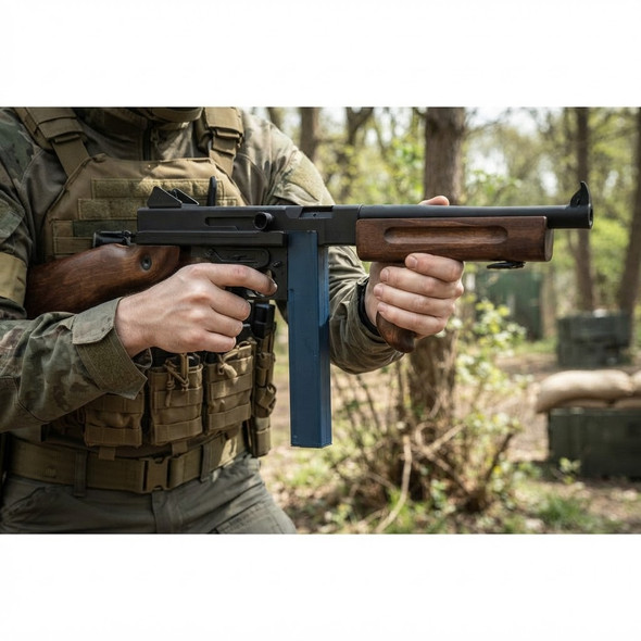 Cyma CM033 Tommy Gun M1A1 AEG Rifle in Blue held by a tactical player in a wooded outdoor setting