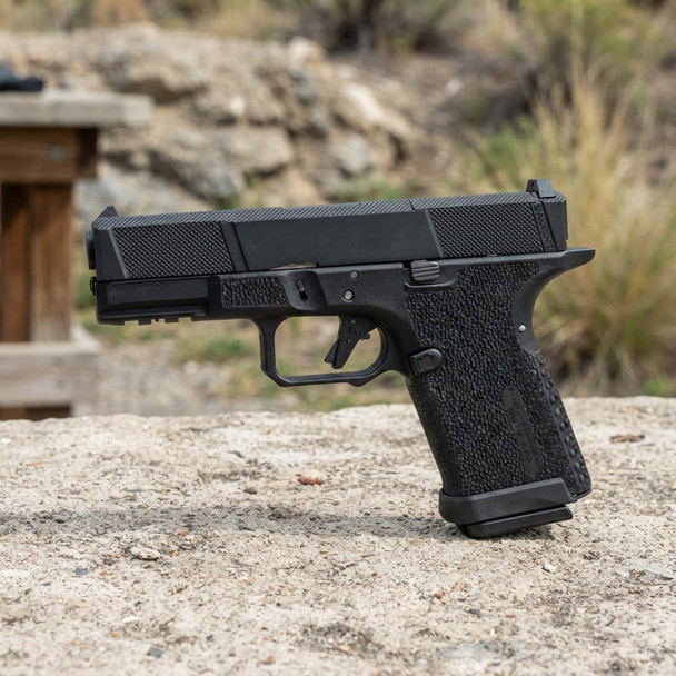 SAI Utility BLU Compact RMR-Cut Slide GBB Pistol - Blackout shown in left-side profile outdoors on a stone surface
