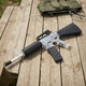 Blackviper B3803 M4 Fully Auto Airsoft Rifle in Clear/Black on a picnic table with safety glasses and vest
