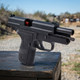 Swiss Arms Navy Compact .40 Gas Blowback Airsoft Pistol in Black with exposed red nozzle at an outdoor range