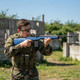 Player in camo aiming the AGM MP008A - M14 AEG Airsoft Rifle AEG in Blue at an outdoor skirmish field
