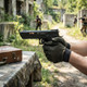Double Bell 303+ John Wick 4 Series Gas Blowback Airsoft Pistol with Wooden Case in Back aimed by gloved hands outdoors