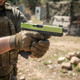 Vorsk EU17 Tactical Gas Blowback Airsoft Pistol with Green Top Slide held two-handed on an outdoor field