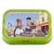 The image features a brightly colored tin of "Sardines à la Tapenade," with an engaging and lively illustration that captures the essence of a bustling French coastal town. In the foreground, two characters are depicted: a woman with curly red hair dressed in a green apron and a young man in a striped shirt holding a guitar, suggesting a lively, artistic atmosphere. The woman appears to be serving or offering a sample to the man, likely a taste of the product within.

The background of the illustration shows a vibrant street scene with buildings typical of a French town, a café sign reading "CAFE DE LA MAIRIE," and the masts of docked boats, hinting at the seaside setting. This backdrop serves to invoke the coastal origins of the tapenade, a spread made from black olives, capers, and anchovies, which is a specialty of the Provence region in France.

At the top of the tin, the product name "SARDINES À LA TAPENADE" is prominently displayed. Below the illustration, further details specify "Sardines with black olive tapenade," clearly indicating the flavoring of the sardines. The net weight is provided as 4.05 oz (115 g). The outer border of the tin is a bright lime green, adding to the tin's eye-catching design and enhancing its shelf appeal. The overall design of the tin suggests a product that is not only flavorful but also rooted in the traditional tastes and vibrant culture of the French Mediterranean.