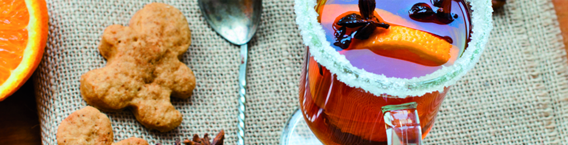 beauty shot of a warm holiday drink with orange slices and gingerbread cookies