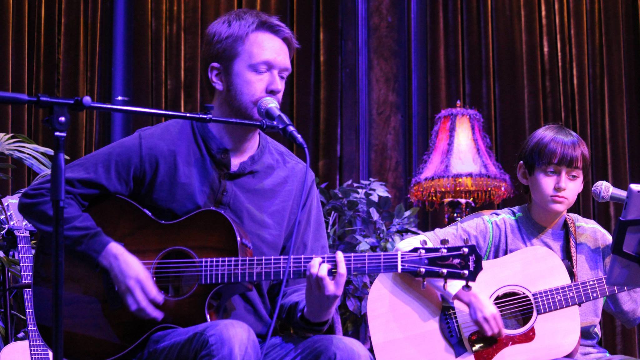 a person and a boy playing guitars