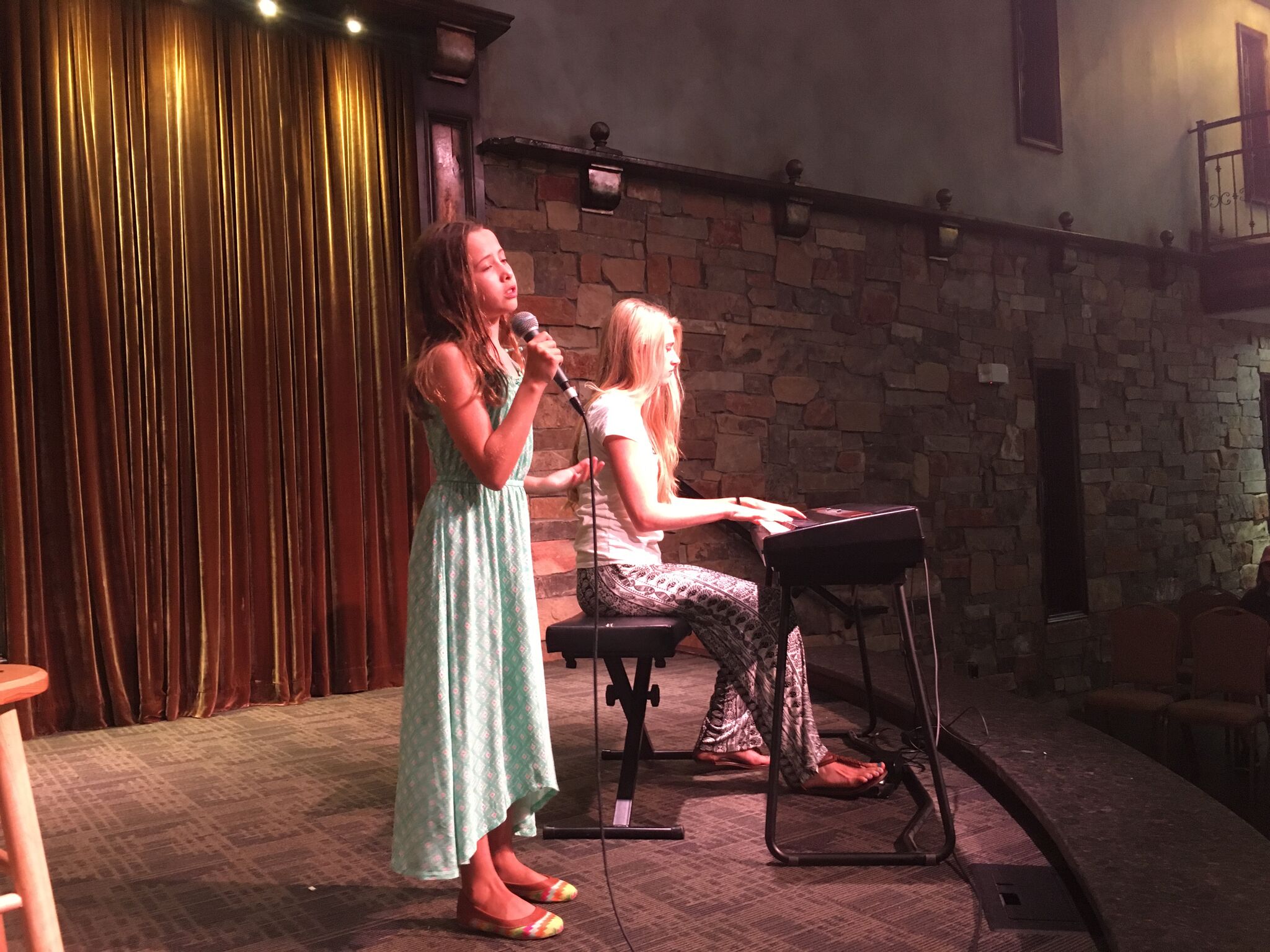 a person singing into a microphone next to a person sitting on a chair