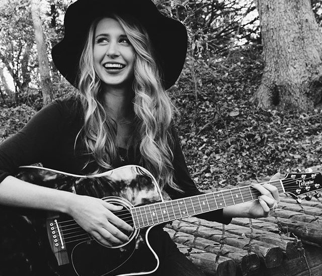 a person with long hair playing a guitar