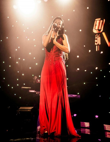 a person in a red dress singing on a stage