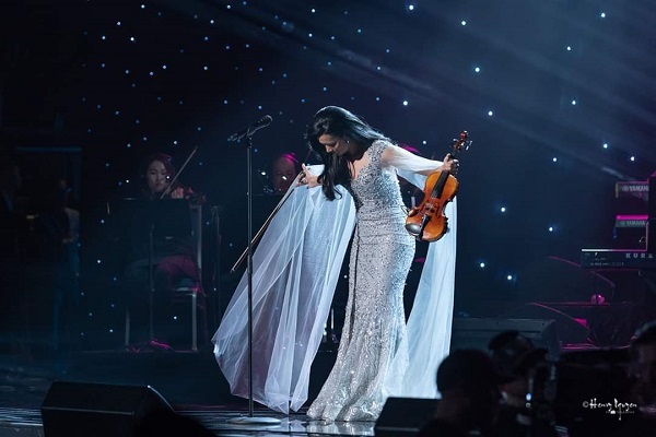 a person in a white dress holding a guitar on a stage