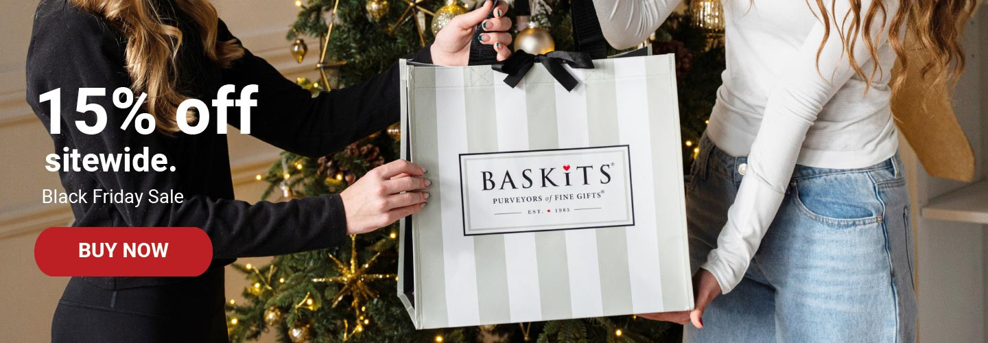A photo of two people holding a Baskits bag in front of a Christmas tree