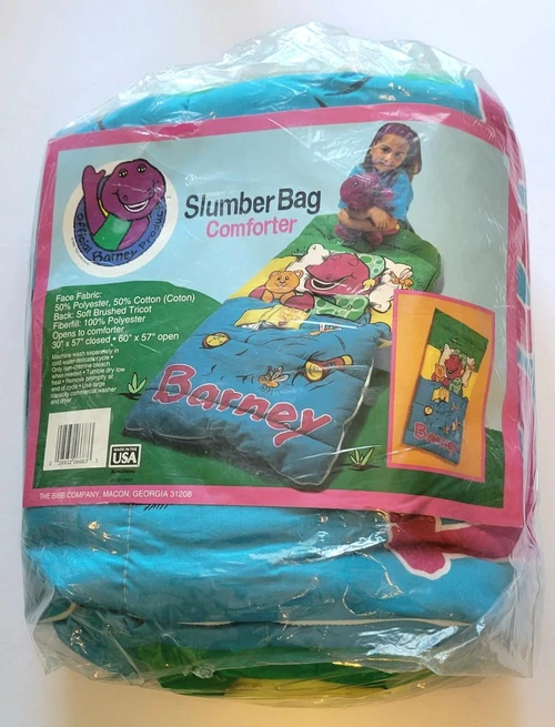 Barney and Friends Slumber Bag Comforter, packaged in clear plastic with colorful graphics of a girl holding a Barney plush and a bed with Barney-themed bedding.