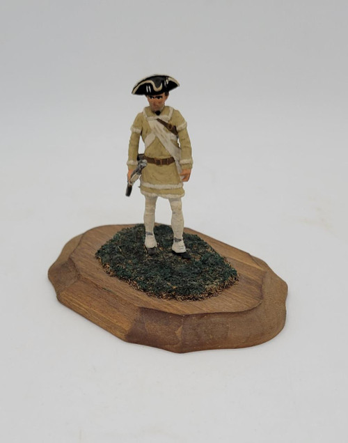 Unknown Colonial American Revolutionary War 2-inch tall diecast figure on wood stand, dressed in colonial military uniform, holding a musket, with detailed accessories and standing on a textured base.