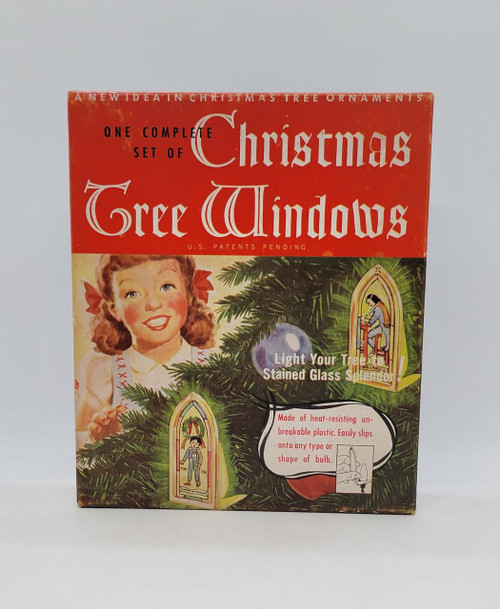Unbranded Vintage 1947 Nativity Scene Complete Set Of Christmas Tree Windows for Tree Lights, red packaging with retro design, featuring a smiling girl, Christmas tree branches, and stained glass window ornaments.