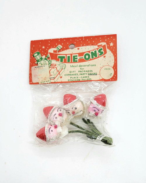 Tie-Ons Vintage Christmas Santa Claus Tie-Ons Made in Japan, small plush Santa figures with red hats and smiling faces, attached to green stems.
