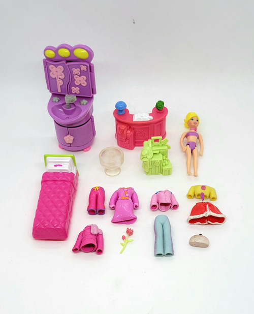 Polly Pocket lot that contains 1 Polly Pocket, 1 bathroom purple vanity, 1 pink desk, 1 red bed, i set of lime green luggage, 2 pair of pants (1 red, 1 blue), 2 jackets (1pink, 1 red), 1 yellow sweater, 1 red shoal, 1 red rose and 1 makeup bag.  The vanity is dated 2008.