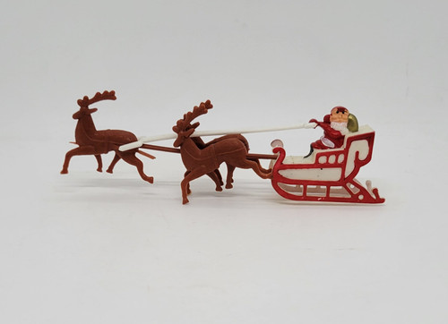 Vintage 1950's plastic Santa Claus and three reindeer pulling sleigh cake topper. The sleigh is white with red with Santa holding a white plastic pole attached to the front reindeer.  The three reindeer is connected to the sleigh with a brown plastic pole which pivots side to side.