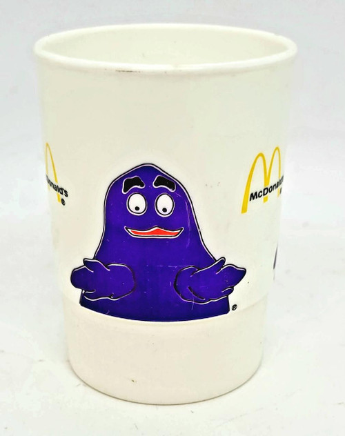 Vintage 1985 McDonald's Grimace Plastic Cup, featuring a purple Grimace character with crossed arms and a friendly expression, branded with McDonald's logo.