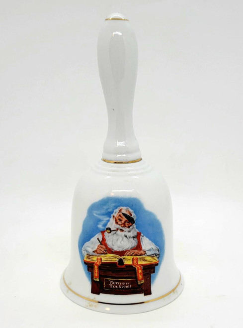 Norman Rockwell Museum 1985 Checking His List Santa Claus Bell, a decorative porcelain bell featuring Santa Claus with a pipe, sitting at a desk with a book, with festive holiday imagery and gold accents.