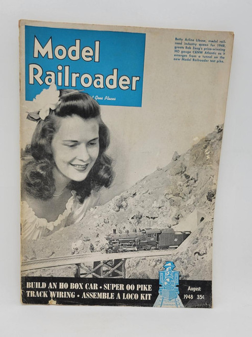 Product Model Railroader - August 1948 (B), vintage magazine cover featuring a smiling woman with curly hair and a model train on a mountain landscape, promoting HO box cars, super 00 pike, track wiring, and loco kit assembly.