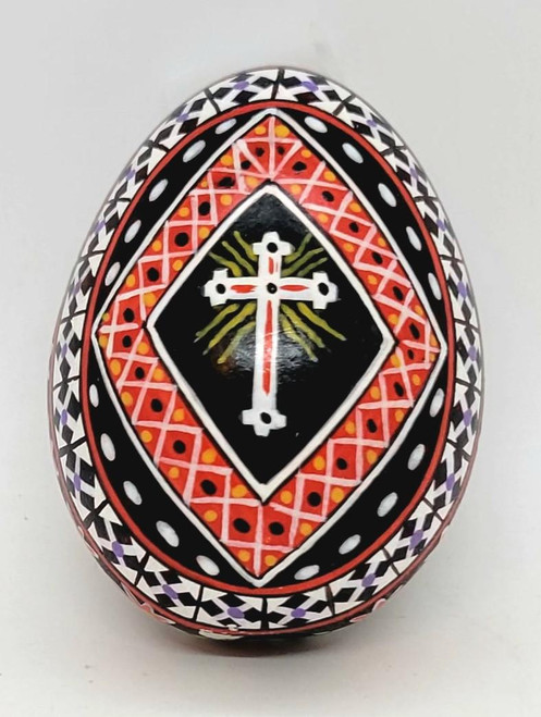 Unknown Pysanka Easter Egg with Christian Cross on it, intricately painted with geometric patterns and vibrant colors.