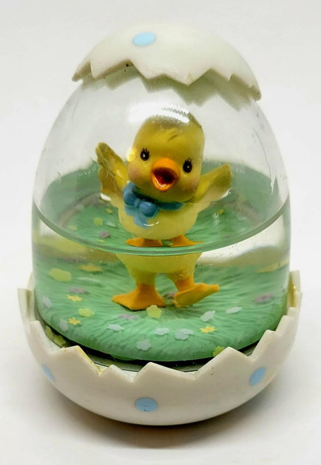 Enesco 1989 Easter Chick in Egg Snowglobe, yellow chick standing inside a clear snow globe with green base and white egg shell top decorated with blue dots.