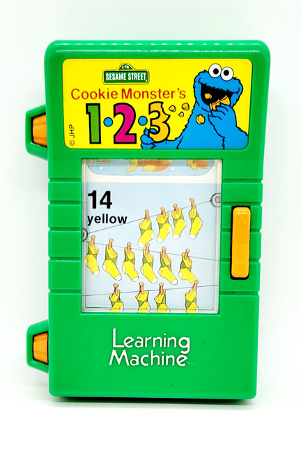 Tyco TYCO Sesame Street Cookie Monster's 1-2-3 Learning Machine, a green electronic educational toy with a colorful Cookie Monster graphic and numbers for children, not working.