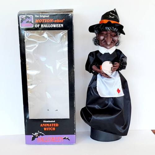 Telco Vintage Telco Motion-ettes of Halloween 17" Illuminated Animated Witch, a spooky witch decoration holding a skull, dressed in a black dress and hat, with a gothic appearance and red eyes, suitable for Halloween decor.
