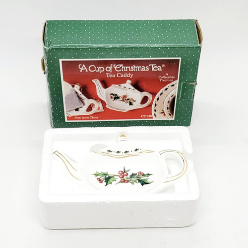 Waldman House Press 1995 A Cup of Christmas Tea Tea Caddy, decorative porcelain teapot with holly and berries design in a white foam packing container with a green cardboard box in the background.
