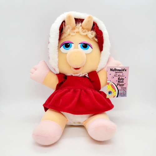 McDonald's 1988 Jim Henson's Muppet Babies Baby Miss Piggy Stuffed Animal, plush toy resembling Baby Miss Piggy with large blue eyes, blonde curly hair, red dress, and hood, sitting on a white background.