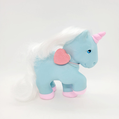 Remco 1983 Pretty Pets Happy Unicorn - Blue, a blue plastic stuffed unicorn toy with white mane and pink horn, featuring a pink heart-shaped tag on its neck.