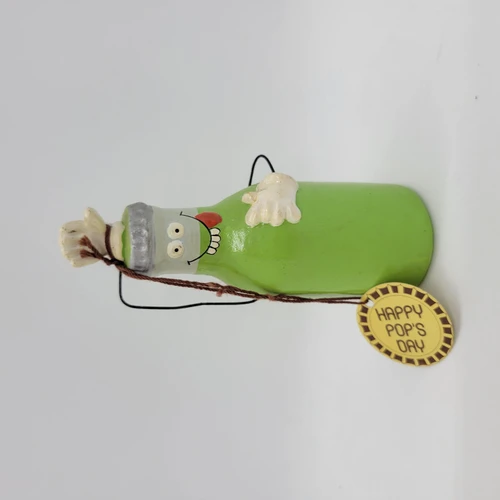 Enesco 1981 Kersten Bros Happy Pop's Day Green Bottle Ceramic Figurine, colorful humorous cartoon-style bottle with a smiling face, chef hat, and a yellow tag reading 'HAPPY POP'S DAY'.