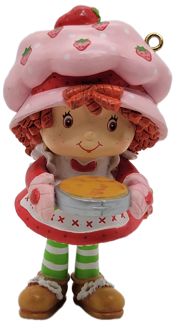 Carlton Heirloom 2004 Christmas ornament Strawberry Shortcake Cooks Up Some Holiday Fun.  The resin ornament features Strawberry Shortcake holding a pie while standing beside her oven.  The ornament stands 3-inches tall.