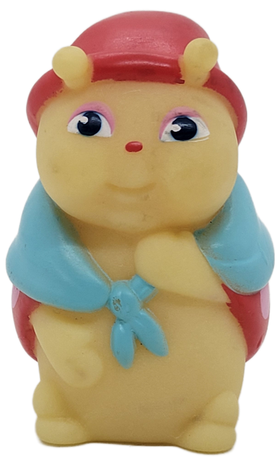 Hasbro 1986 first series of Glo Friends rubber toy figure of Glo Grannybug.  Glo Grannybug stands 3-inches tall and is wearing a red with pink top, red stocking hat and a blue blanket over her shoulders. Eight friends made up the original series of Glo Friends, originally released by Hasbro's Pre-School division.