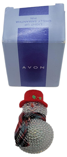 AVON 2001 Light Up Chilly Samantha Snowman Pin, sparkling snowman pin with a red hat, plaid scarf, and light-up feature, in front of its blue box packaging.