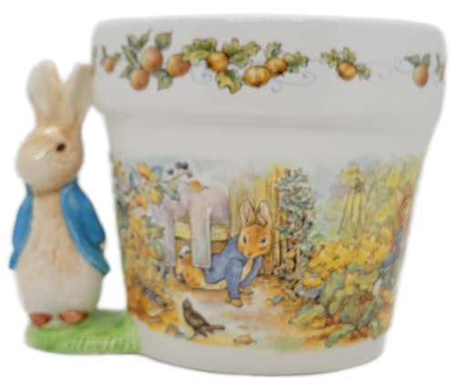 Telefora 1997 ceramic flower pot featuring Beatrix Potter Peter Rabbit.  The ceramic planter is decorated with a scene from Peter Rabbit tale.  The planter also has a 4-inch tall Peter Rabbit on the right side  that also creates a small handle.  The planter has a 5-inch opening to place plant or pot.
