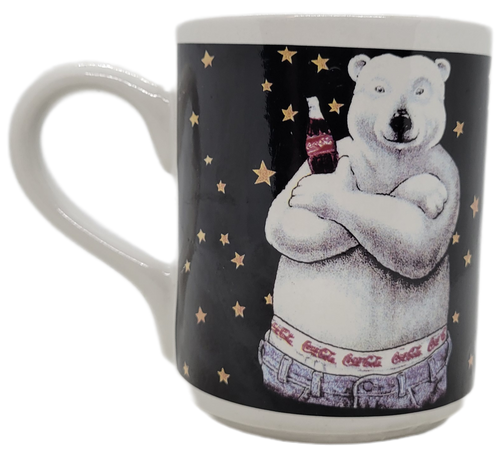Gibson 1996 Coca-Cola ceramic mug featuring a Polar Bear with arms crossed holding a bottle of Coca-Cola.  The polar bear is wearing jeans with Coca-Cola waist band with a black background with yellow stars.