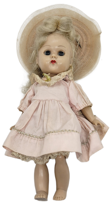 Vintage Vogue Ginny doll that stands 7-inches tall.  The doll is wearing pink dress and hat with blonde hair and red lips.  The doll was Made in USA.
