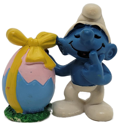 Smurfs Vintage 1984 PEYO 2.0490 Smurf with Easter Egg (Yellow Bow) PVC Figure, colorful blue Smurf holding a decorated Easter egg with a yellow bow, wearing white pants and a white hat.