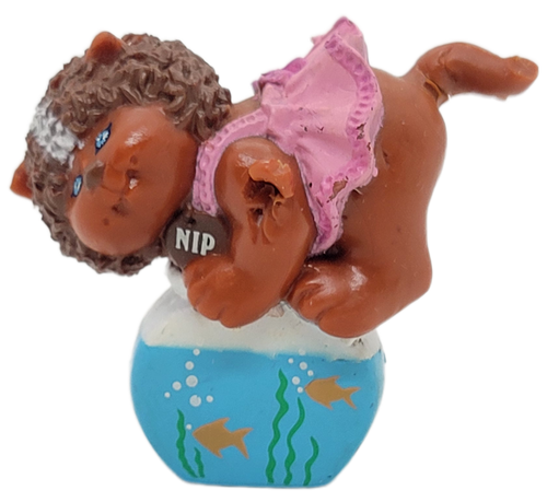 Cabbage Patch Kids 1985 Koosas PVC figure of a dark brown cat with fish bowl named Kip.  This variation of Kip is wearing pink dress and standing on a fish bowl by OAA.  The figure stands 2-inches tall.