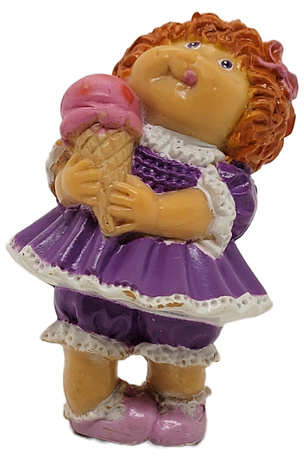 Cabbage Patch Kids 1984 PVC figure of a girl wearing purple with white trim dress and pink shoes by OAA.  The red hair girl is holding an ice cream cone in her hands.  The figure stands 2.25-inches tall.