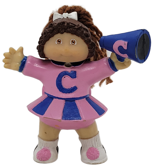 Cabbage Patch Kids 1985 figure of a brown yarn hair girl wearing a pink cheerleader uniform with blue stripes by OAA.  The girl is holding a blue megaphone in her left hand. The figure stands 3-inches tall.