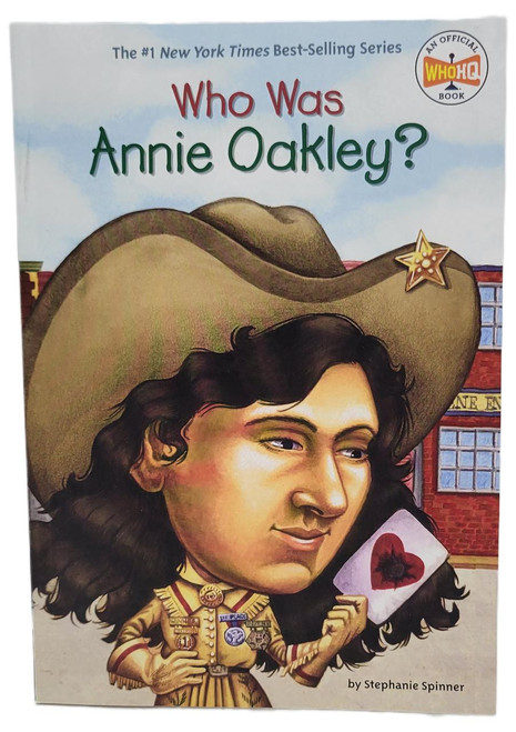 Product Penguin Workshop Who Was Annie Oakley? by Stephanie Spinner Paperback 2002, illustrated book cover featuring a cartoon portrait of Annie Oakley with a large cowboy hat and a playing card with a heart.