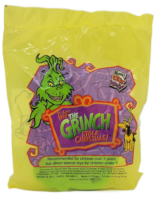 Wendy's Kids' Meal Toy 2000 Dr. Seuss’ How the Grinch Stole Christmas Grinch Sticker Dispenser, yellow packaging featuring a cartoon Grinch illustration, a small dog, and colorful text.